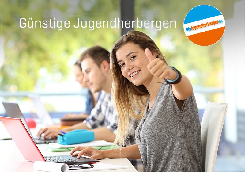 Junge Frau am Laptop zeigt Daumen hoch. Günstige Jugendherbergen.