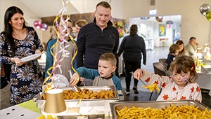 Familie am Büfett der Jugendherberge Trier. Kinder greifen bei Pommes und Nuggets gerne zu.